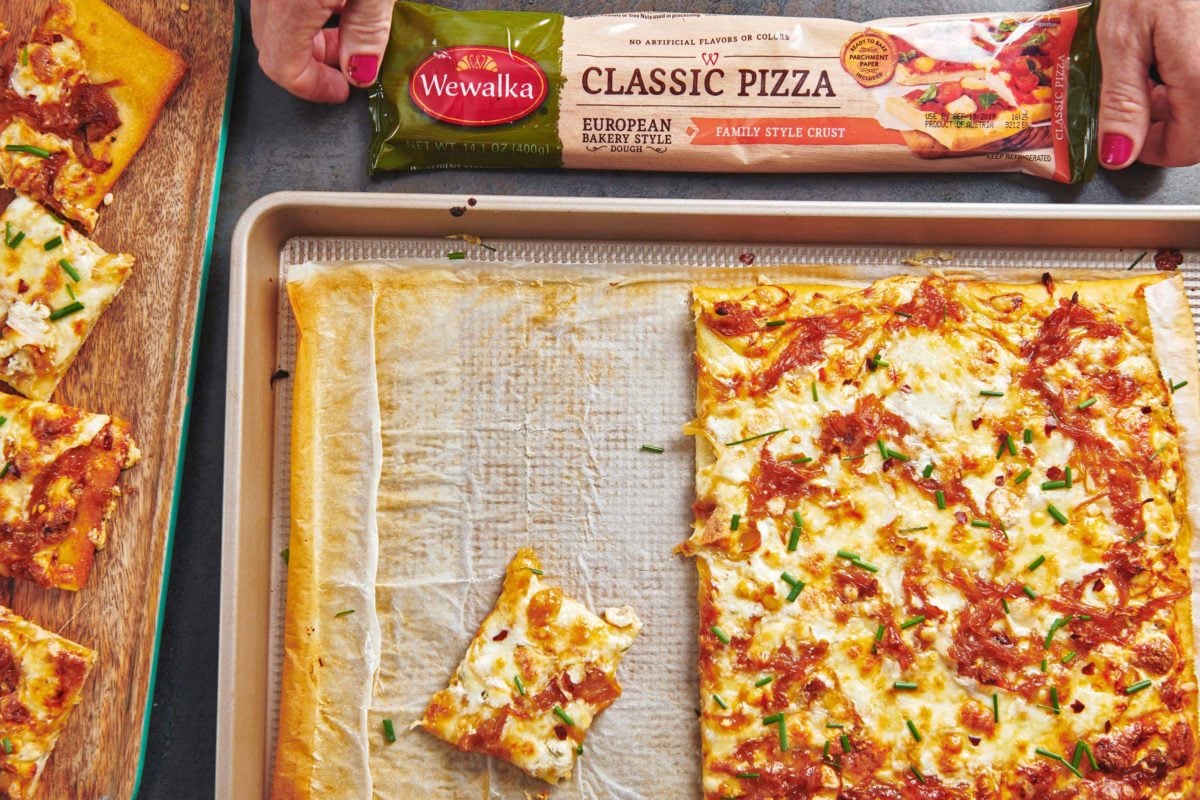 Half-eaten Four Cheese Pizza with Caramelized Onions next to a bag of Wewalka pizza dough.