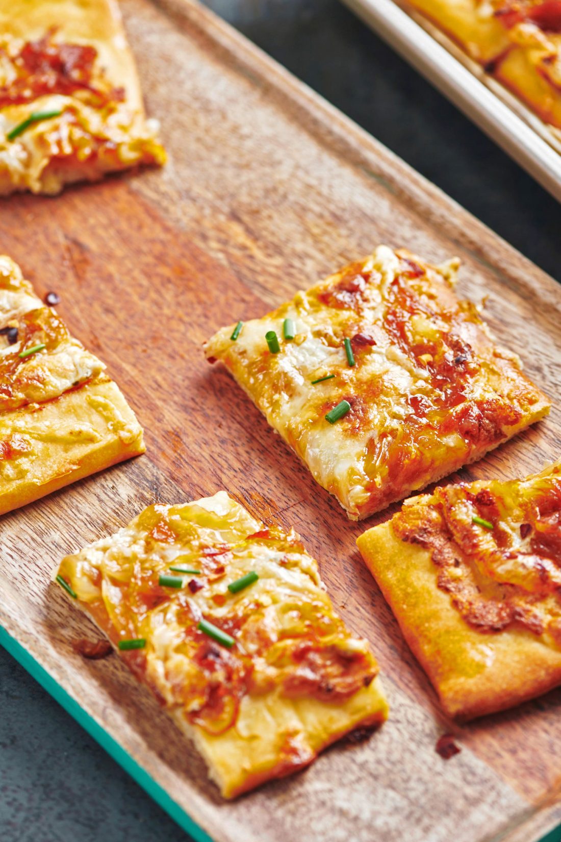 Slices of Four Cheese Pizza with Caramelized Onions on a wooden plate.