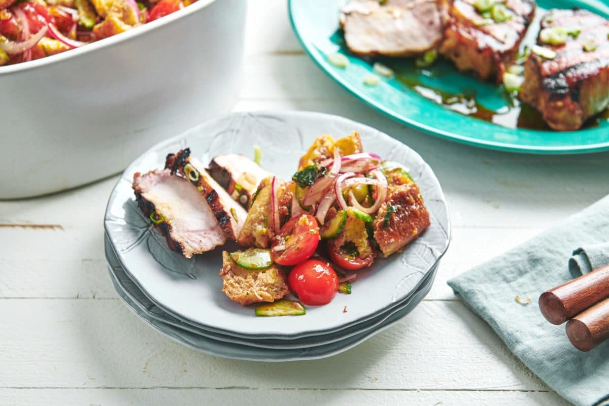 Soy-Ginger Pork Chop and panzanella on a stack of plates.