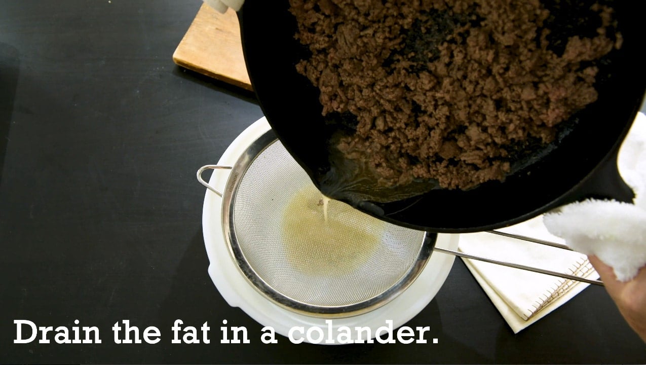 Draining fat from ground beef into a colander.