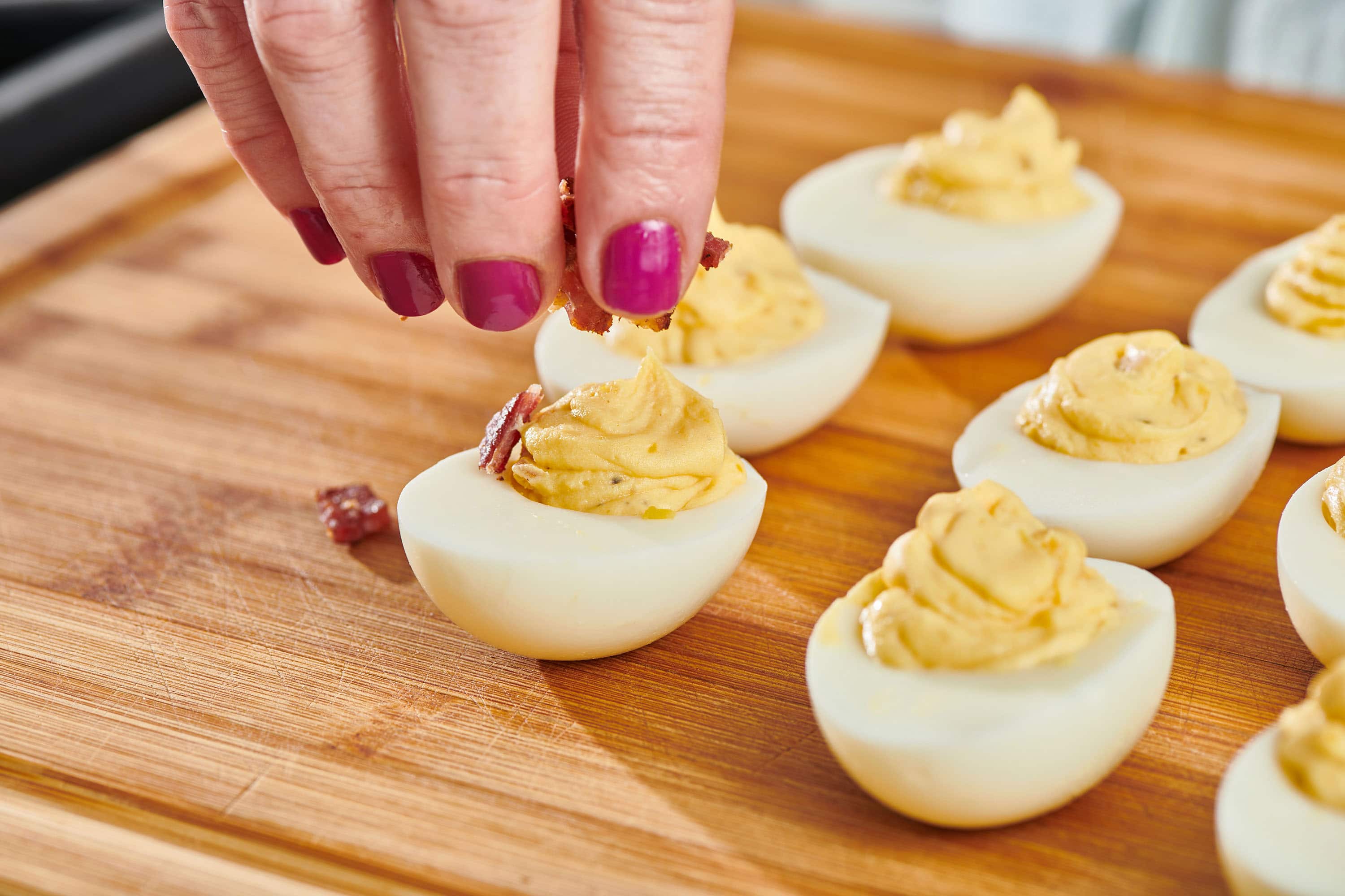 Adding bacon to deviled eggs.