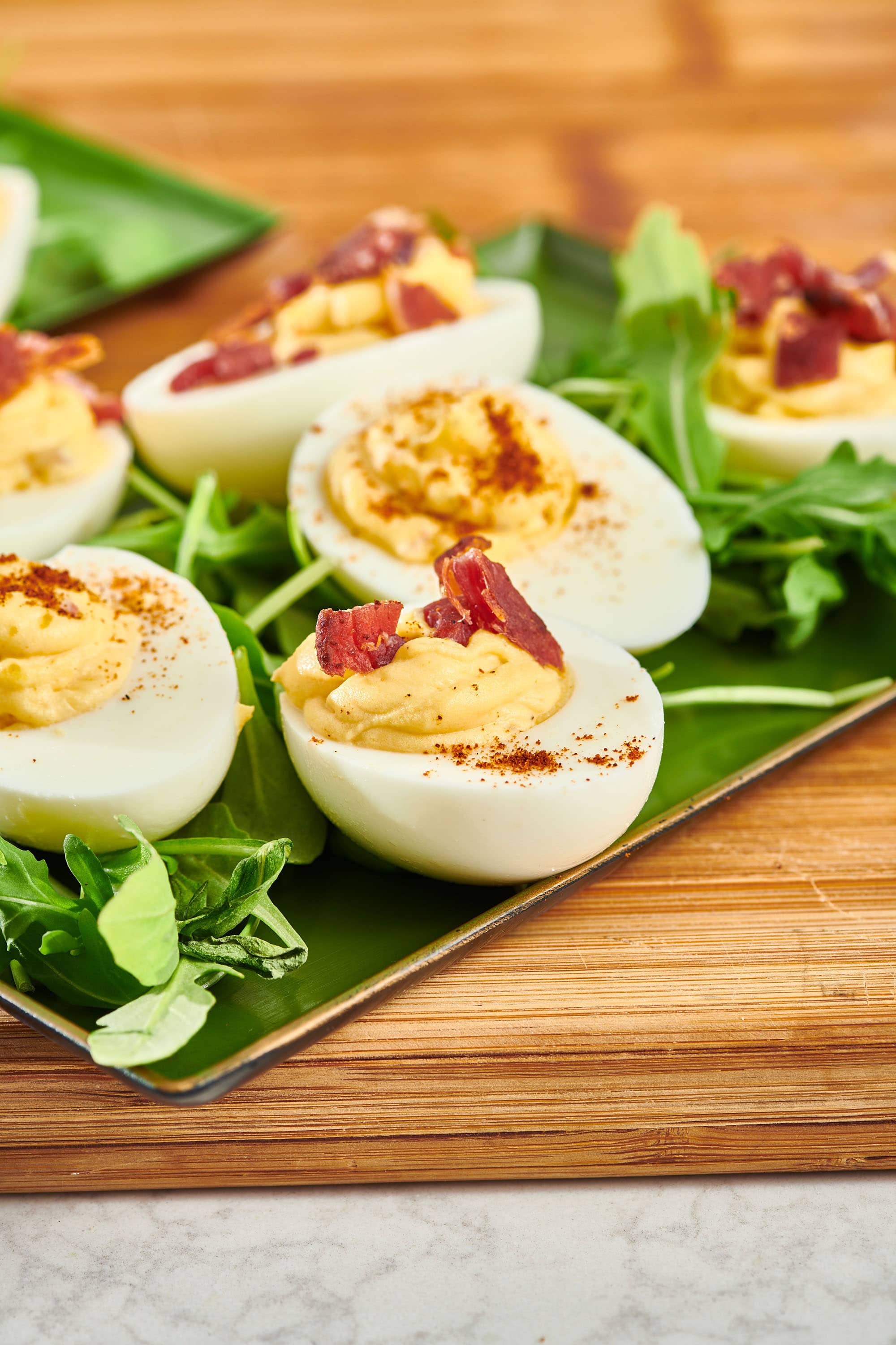 Deviled Eggs with crumbled bacon on a green plate.