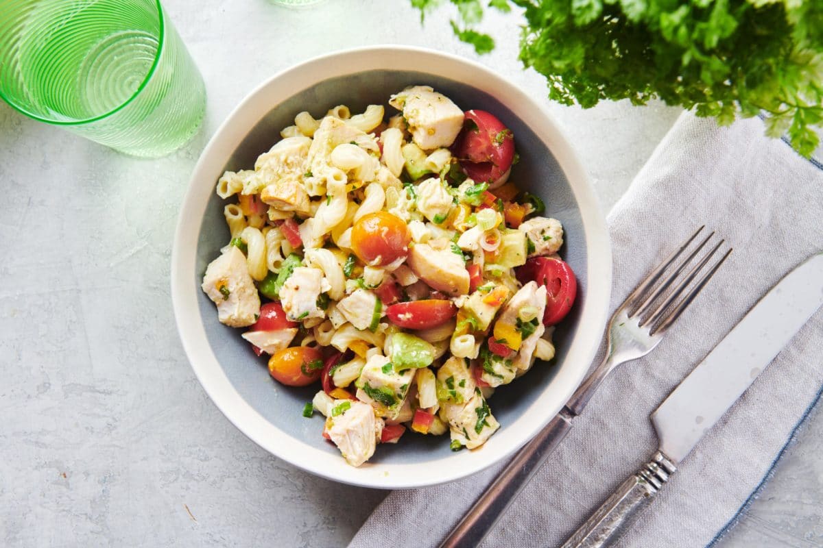 Table setting with a bowl of Pasta Salad with Chicken and a cloth napkin.