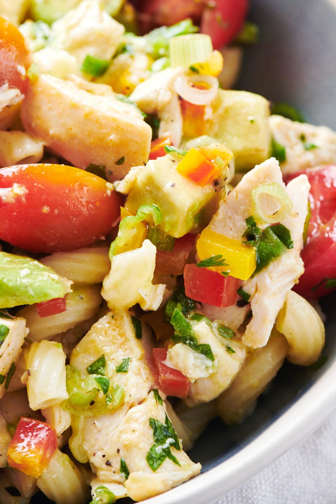 Pasta Salad with Chicken, Avocado and Tomato heaped in a bowl.