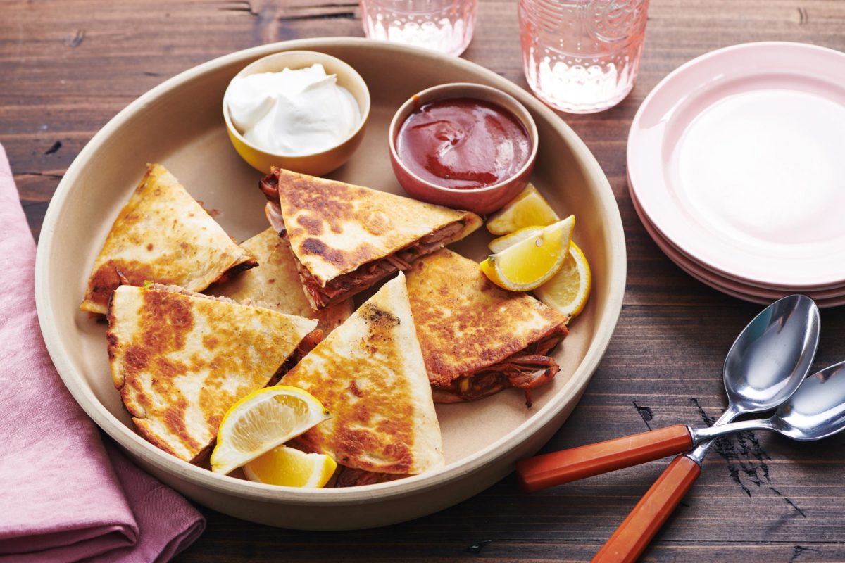 Pulled Pork Quesadillas with small bowls of barbecue sauce and sour cream.