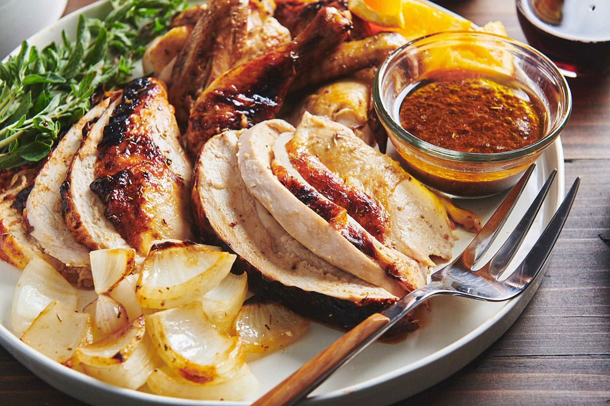 Honey-glazed roasted chicken sliced on plate with sides.