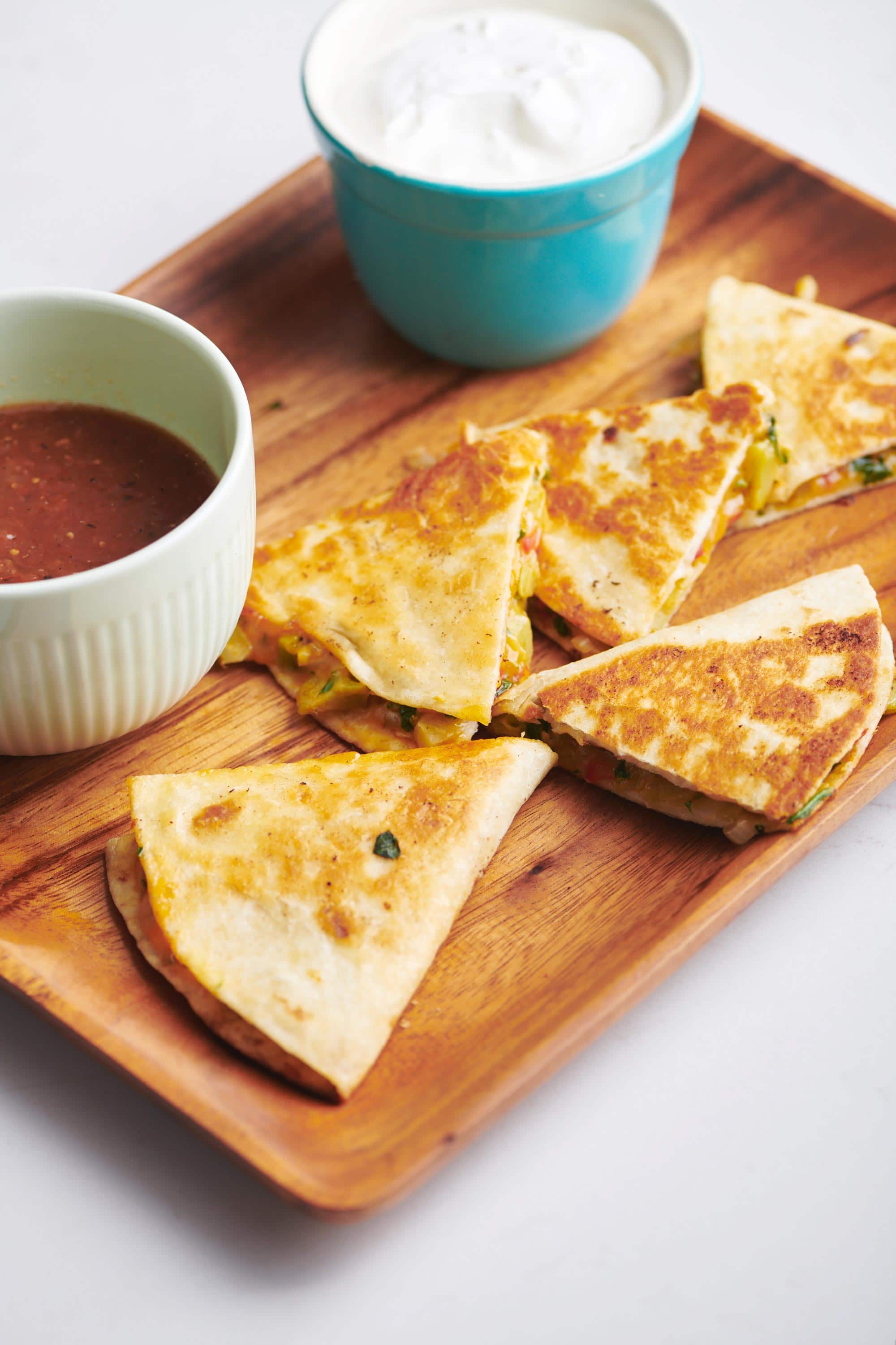 Wooden tray of Vegetable Quesadillas and dips.