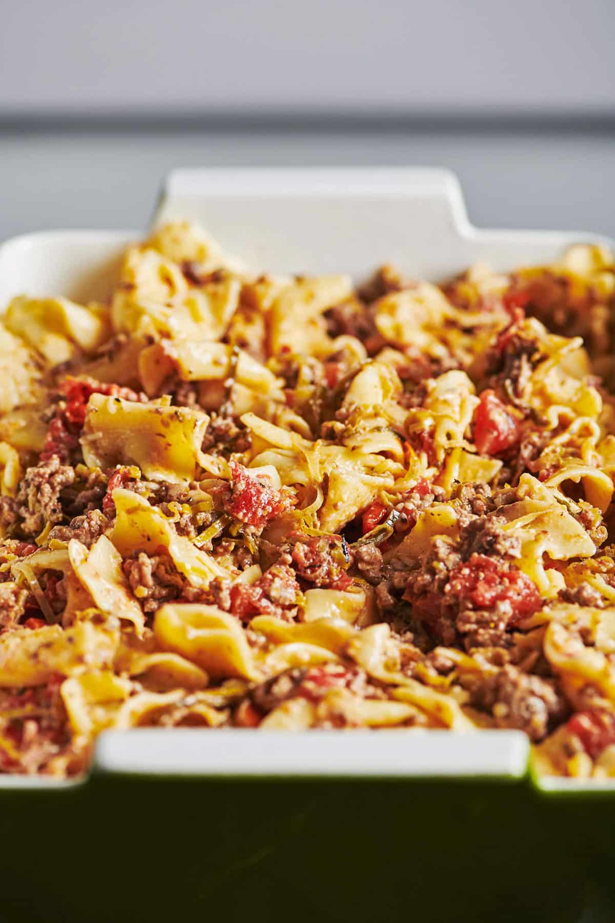 White and green baking dish of Beef and Three Cheese Noodle Casserole.