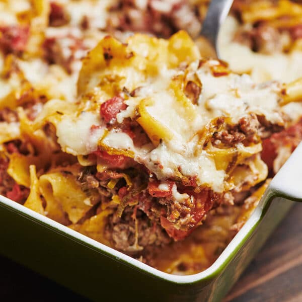 Casserole with beef, cheese, and noodles in green baking dish.