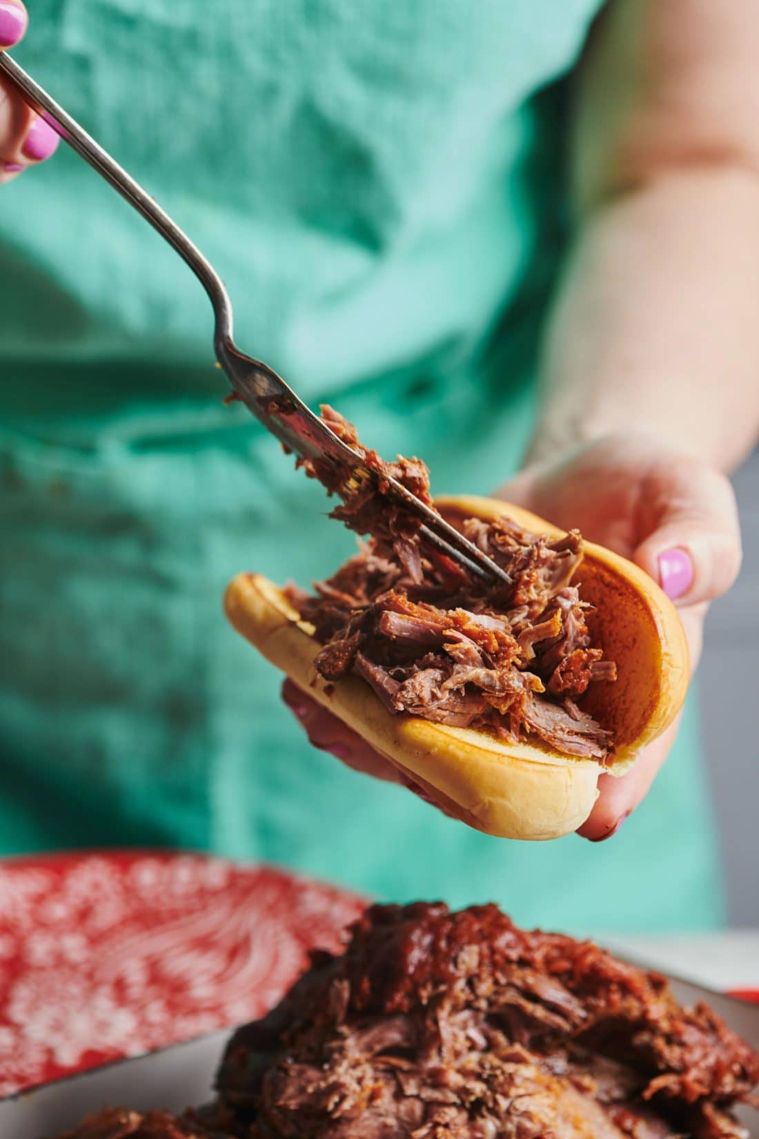 Fork scooping Pulled Lamb onto a bun.