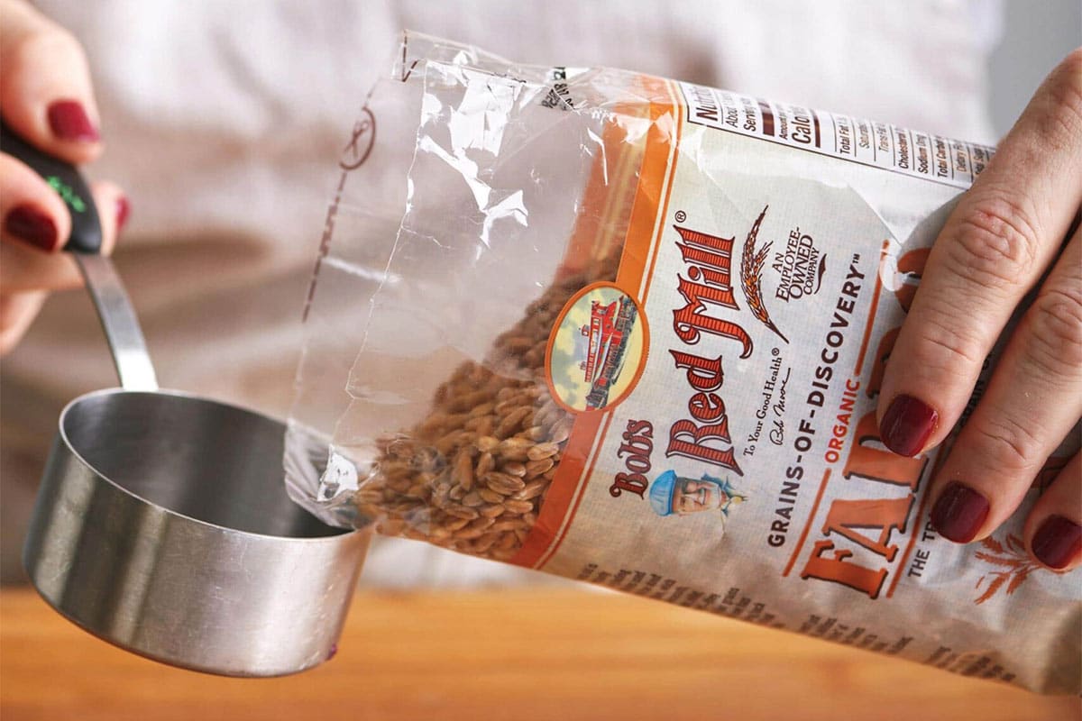 Woman pouring Bob's Red Mill Farro into a measuring cup.