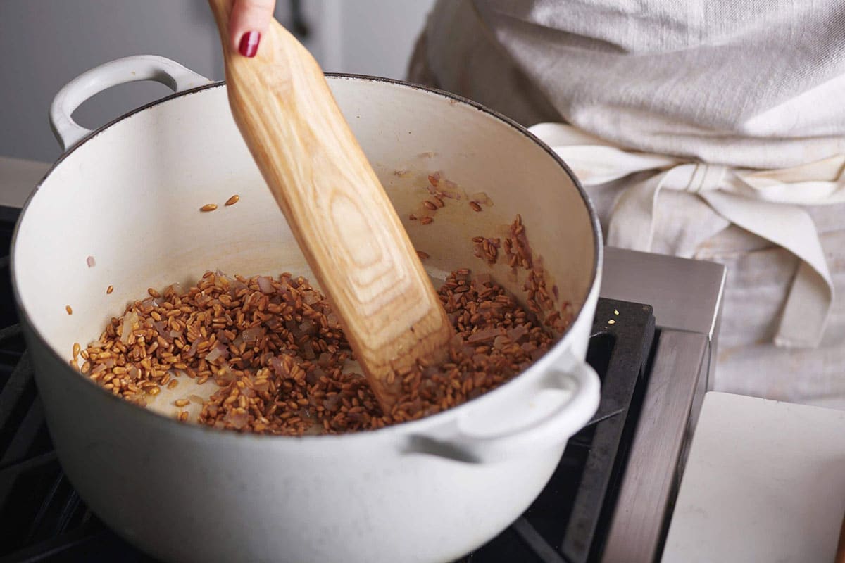 Woman stirring farro in a Dutch Oven.