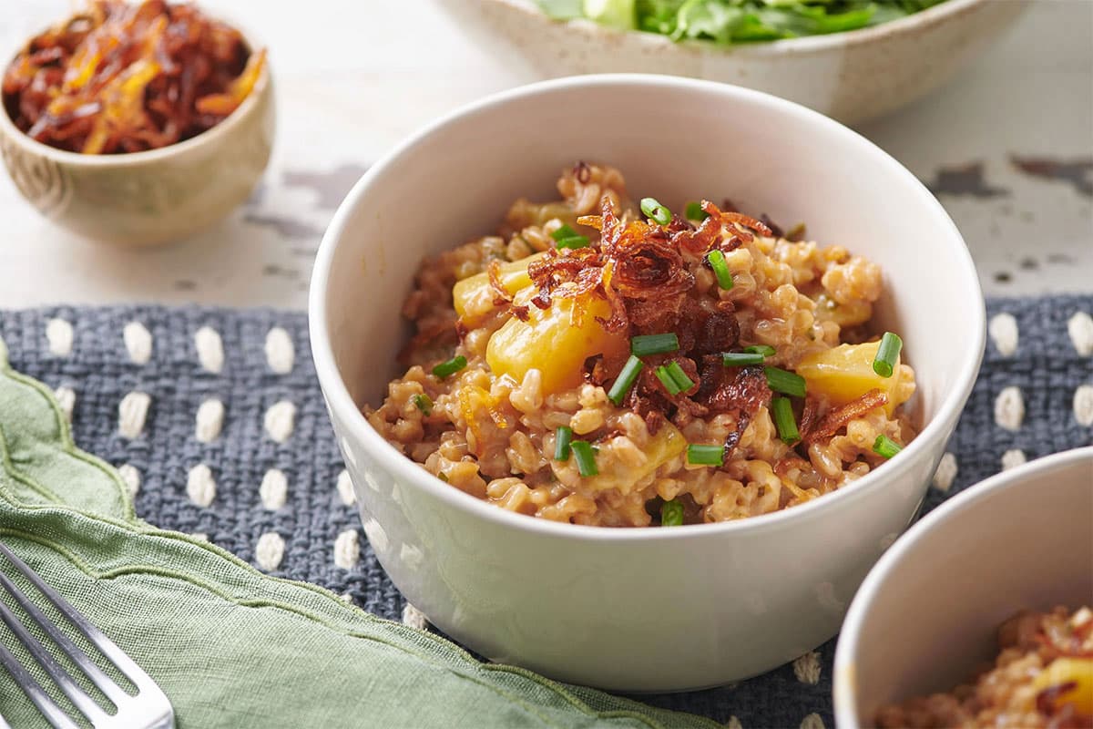 White bowls of Farrotto with Golden Beets, Mixed Herbs and Crispy Shallots.