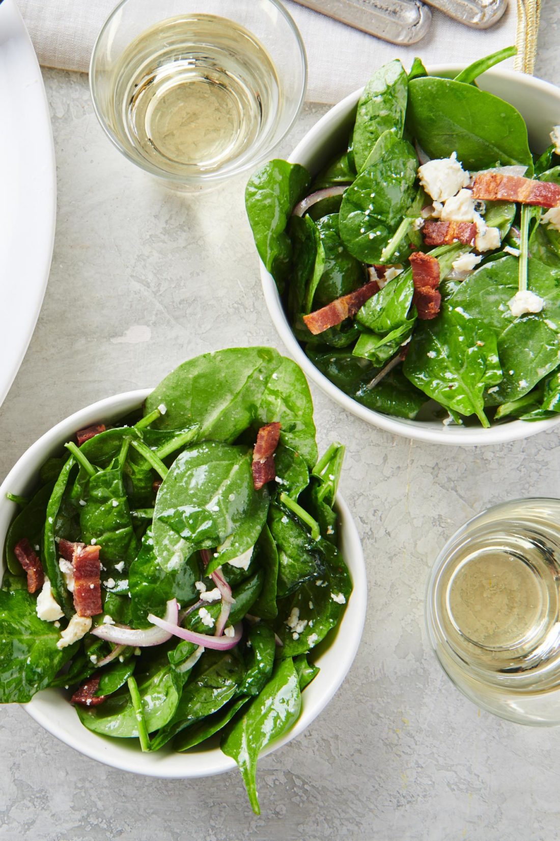 Two bowls of Spinach Salad with Bacon and Blue Cheese.