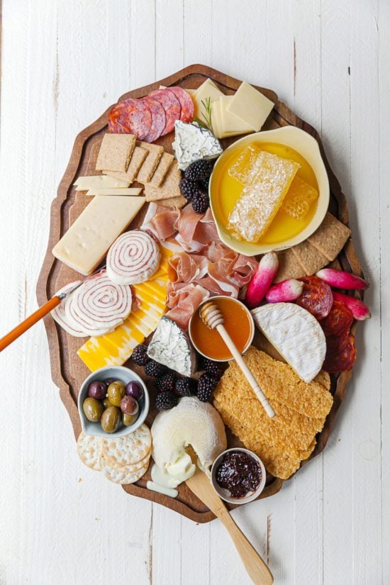 Graze Board with honey, meat, cheese, olives, fruit, crackers, and other foods.