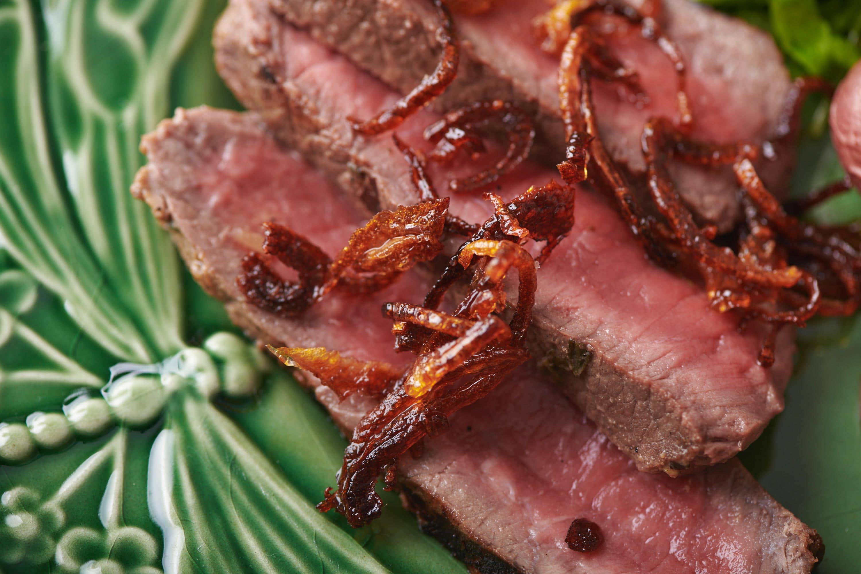 Sliced steak with fried shallots.