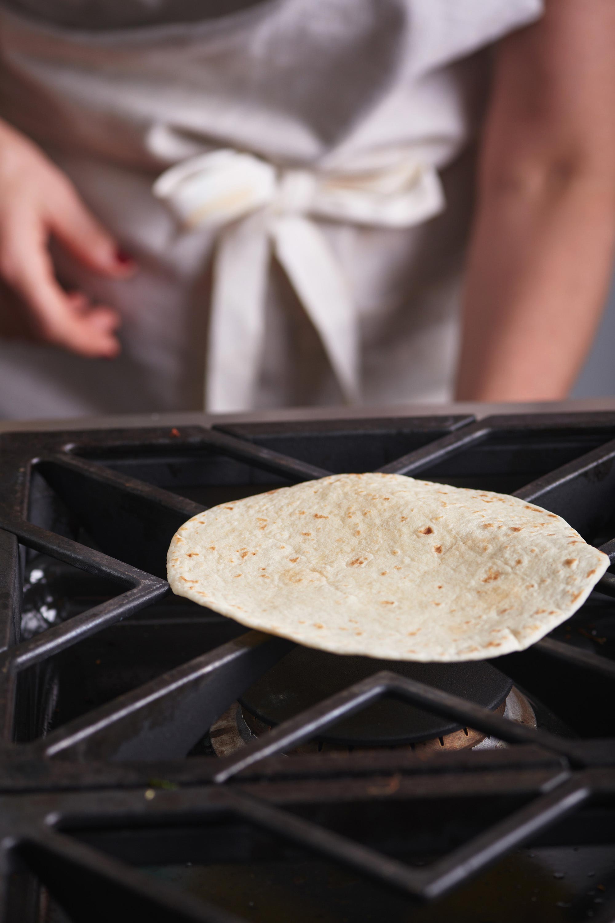 Tortilla warming directly on a gas stove.