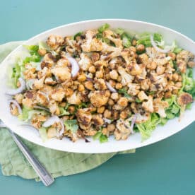 Roasted Cauliflower and Chickpea Salad with Tahini Dressing in white bowl on table.
