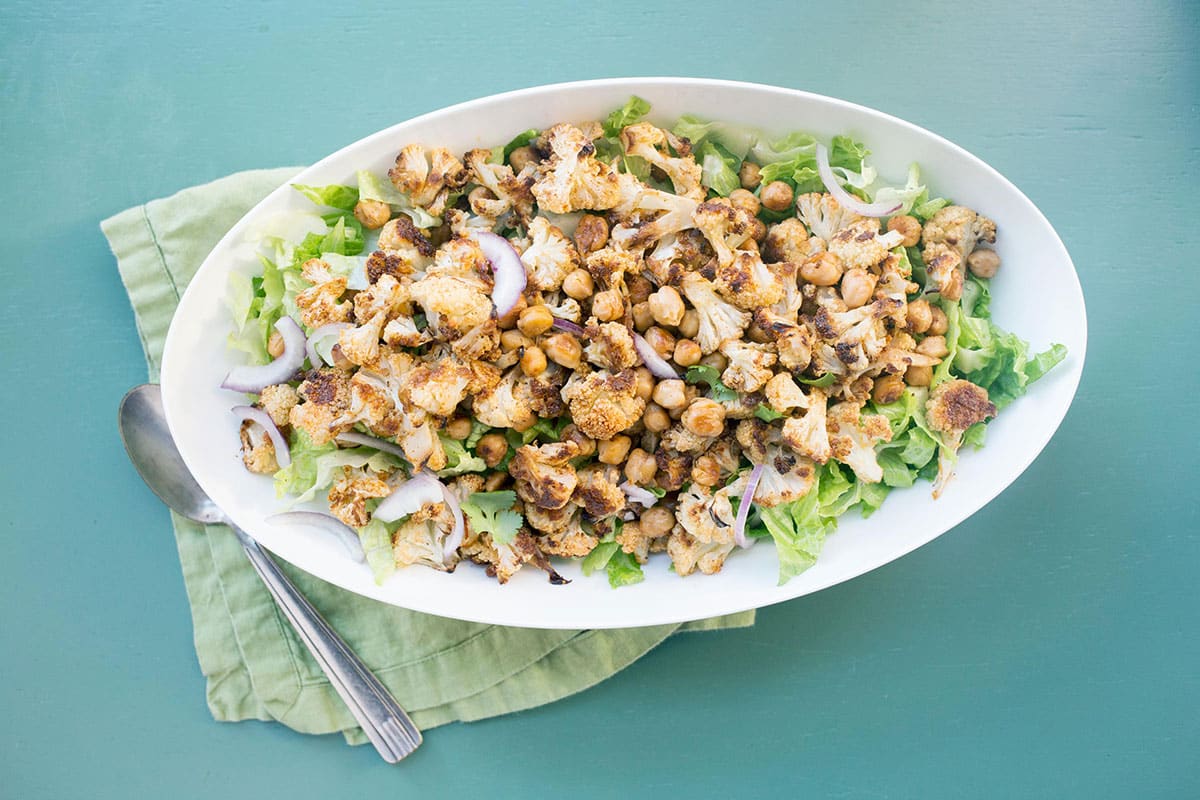 Roasted Cauliflower and Chickpea Salad with Tahini Dressing in white bowl on table.