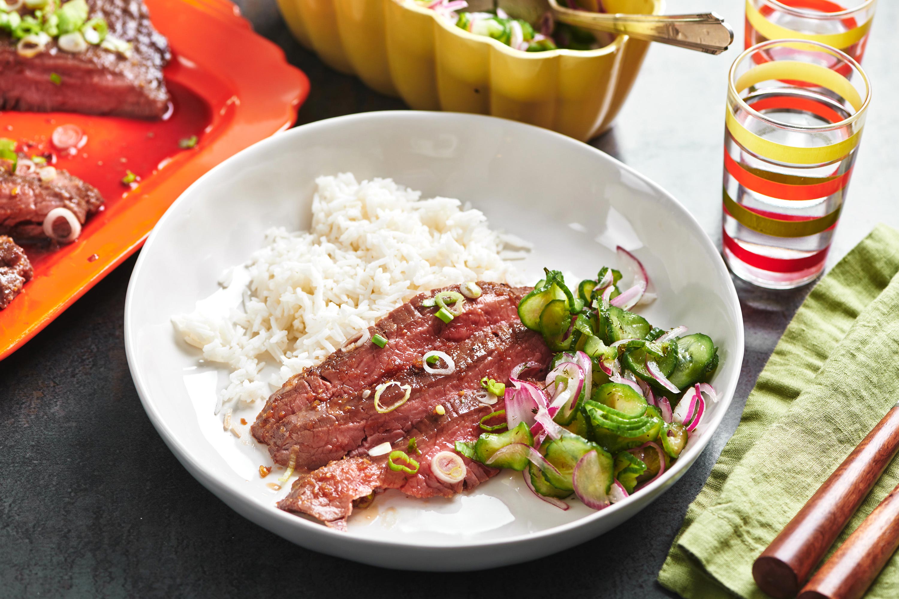 Rice, salad, and Soy-Ginger Flank Steak on a white plate.