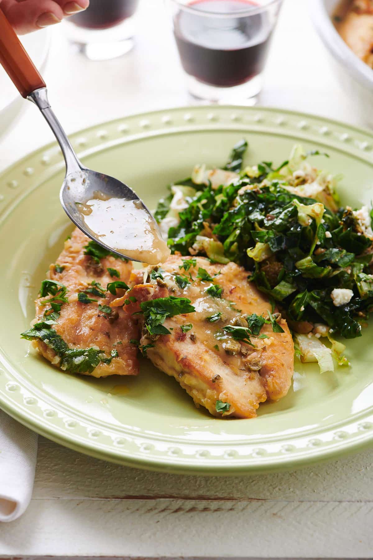 Spoon putting sauce on Chicken Piccata.