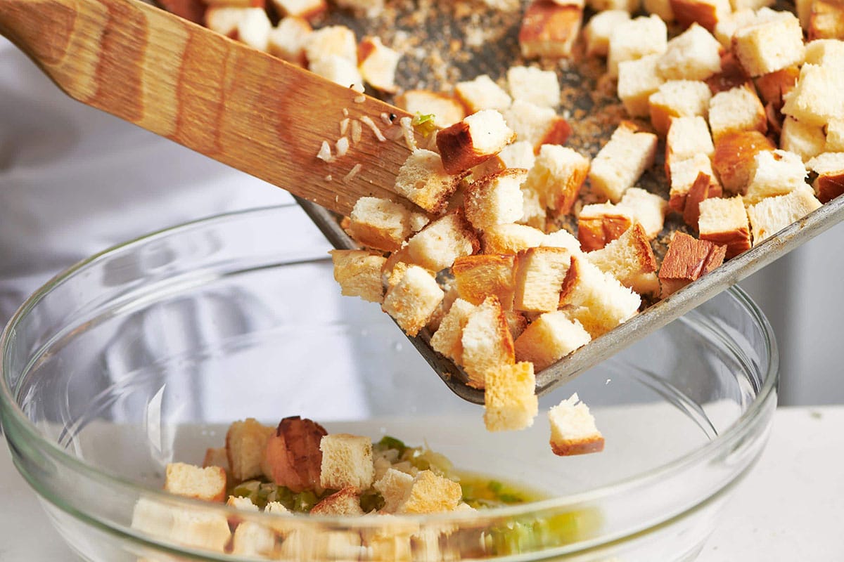 Dried bread cubes pouring into a glass bowl.