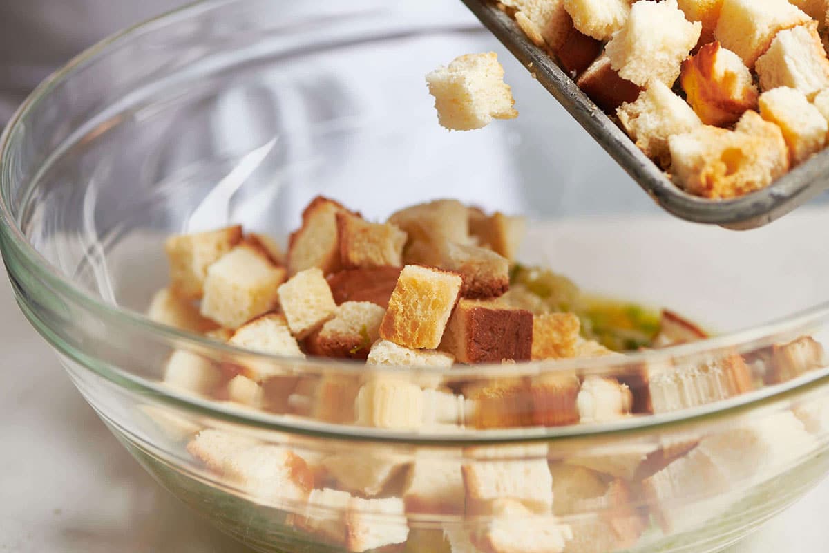 Pouring bread cubes into glass bowl.