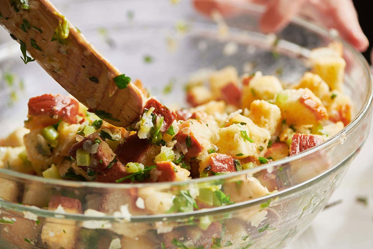 Woman tossing bowl of bread and seasonings for stuffing.