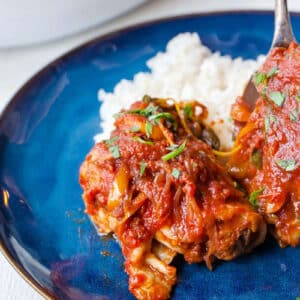 Instant Pot Chicken Cacciatore over rice on blue plate.