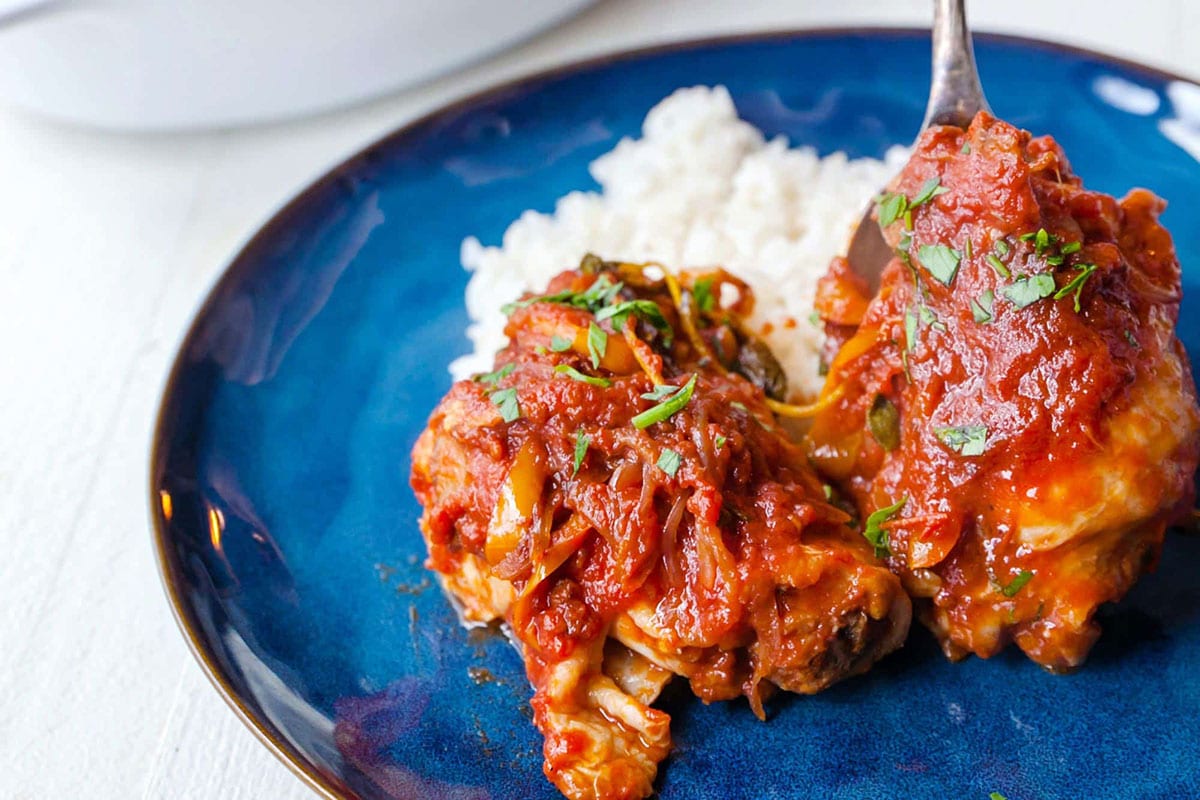 Instant Pot Chicken Cacciatore over rice on blue plate.