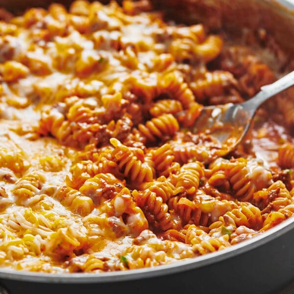 Spoon in pan of beef enchilada casserole with pasta.