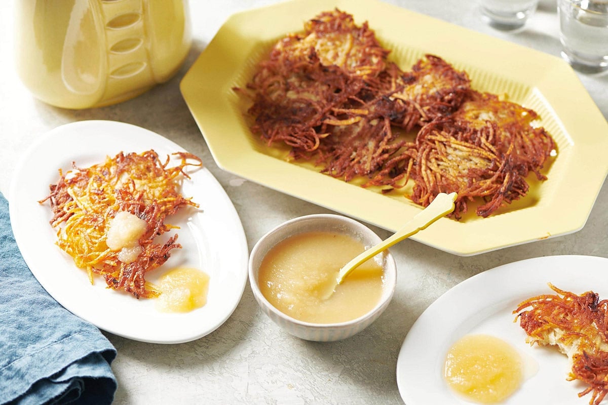Crispy Jewish potato pancakes (latkes) on plates with applesauce.