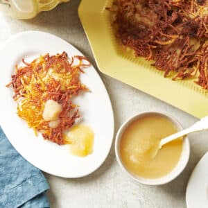 Potato pancakes on plate and platter with apple sauce