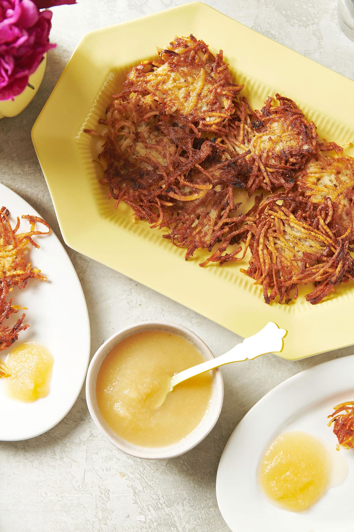 Homemade Jewish latkes on plate with bowl of applesauce.