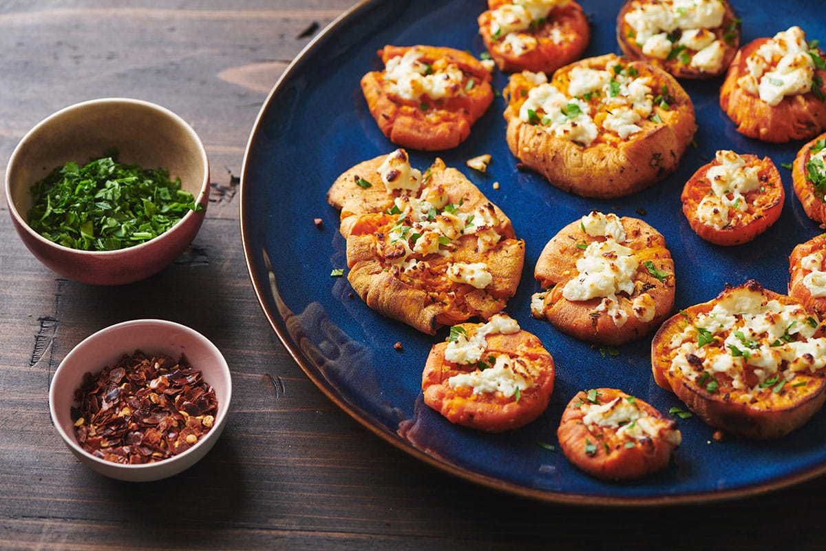 Smashed Garlic Butter Sweet Potatoes with Feta on a blue plate.