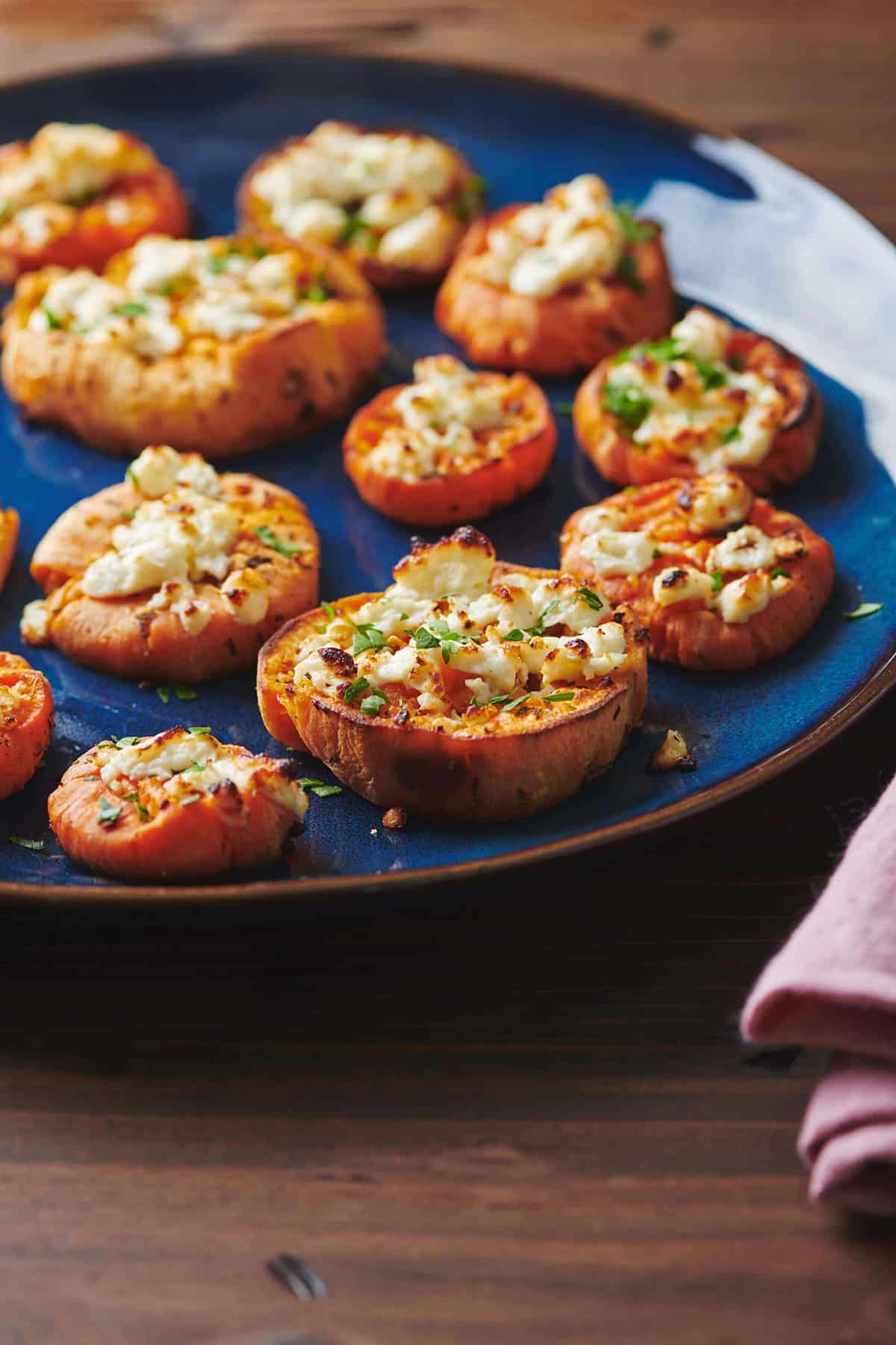 Smashed Garlic Butter Sweet Potatoes with Feta on a blue plate.