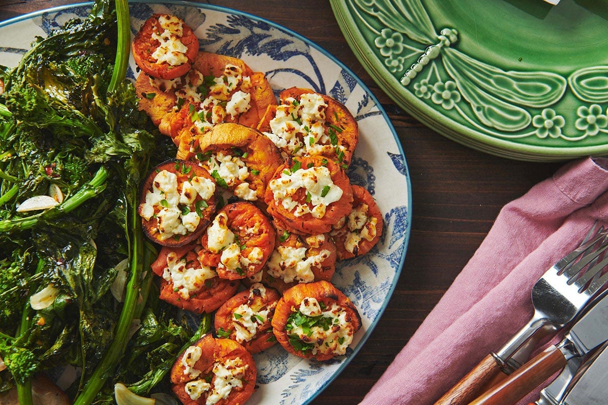 Smashed Garlic Butter Sweet Potatoes with Feta on a blue and white plate.