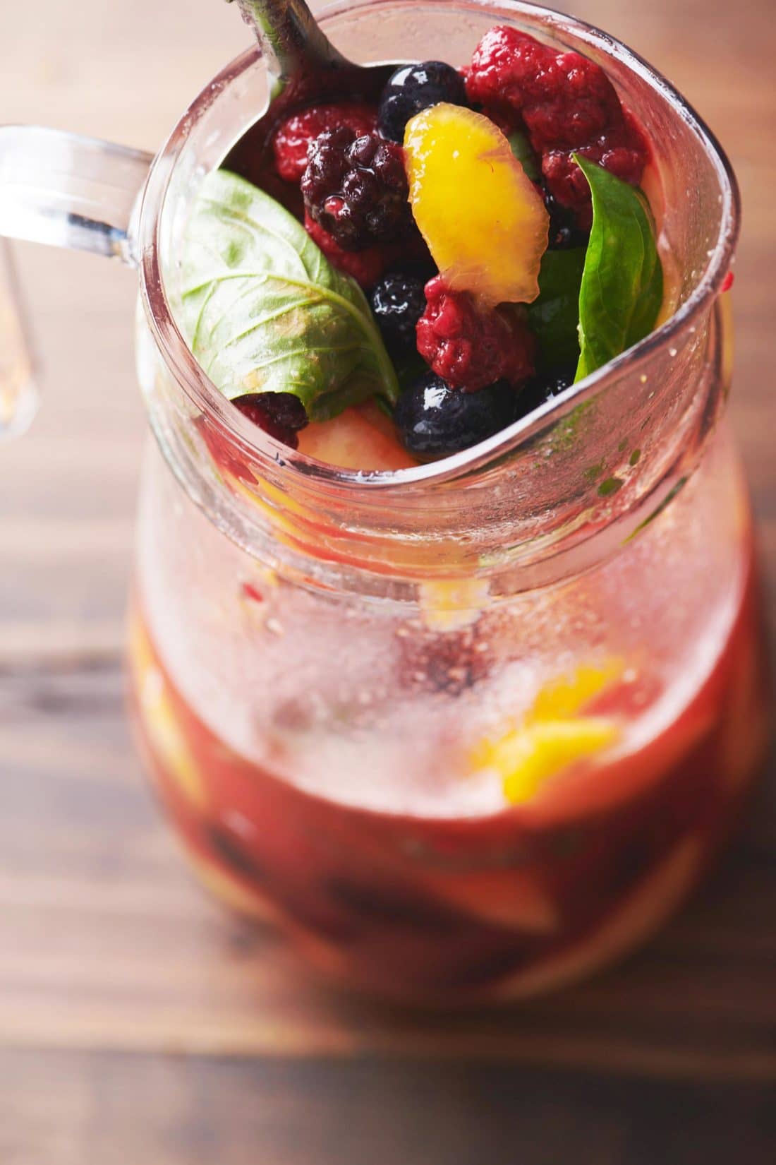 Spoon in a pitcher of Fruit and Berry Sangria.