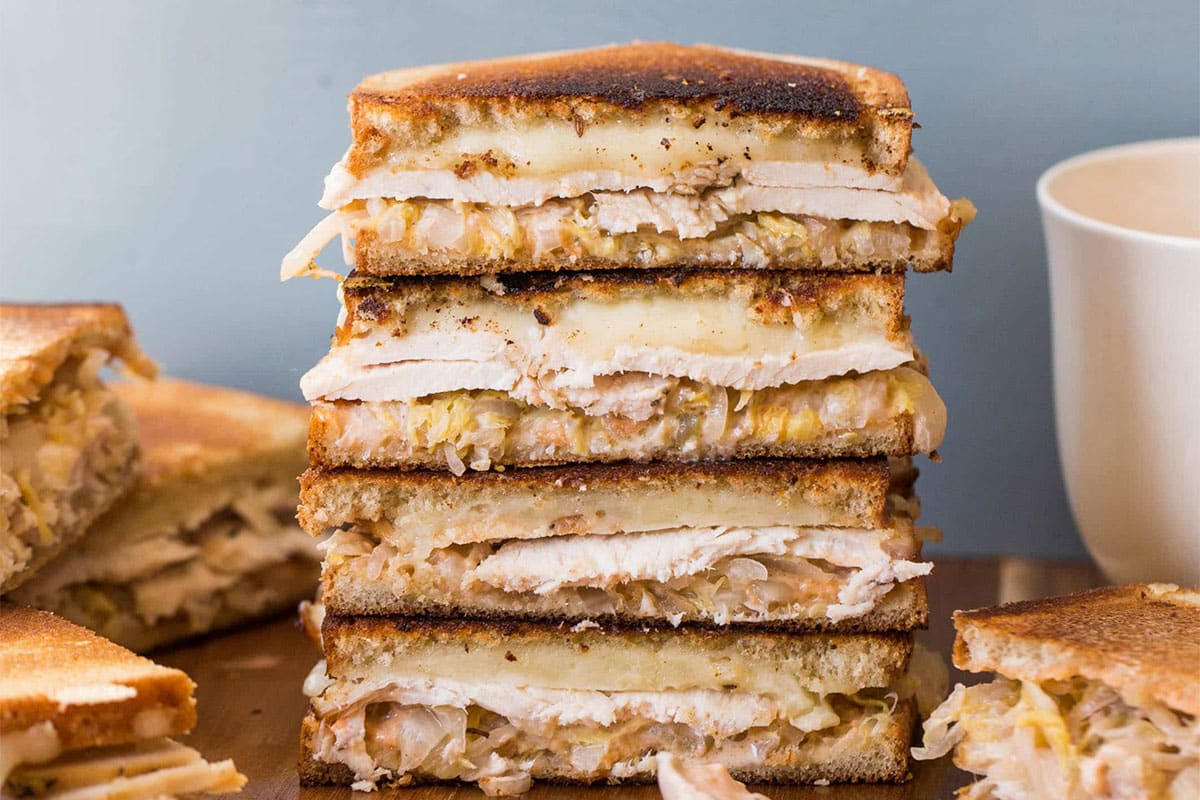 Stack of turkey Reuben sandwiches on cutting board.