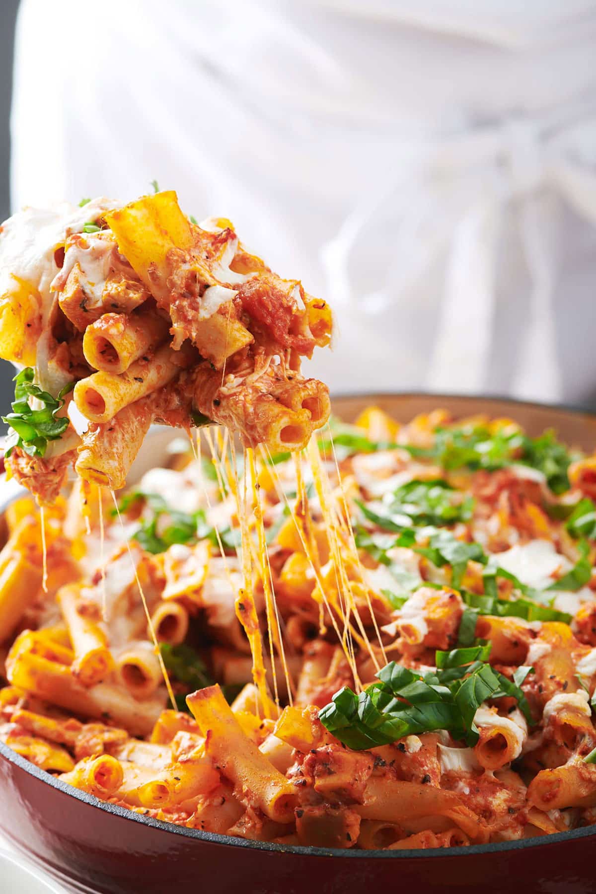 Serving baked chicken Parmesan with ziti pasta and melty cheese.