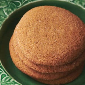 Homemade gingersnap cookies stacked on green plate.