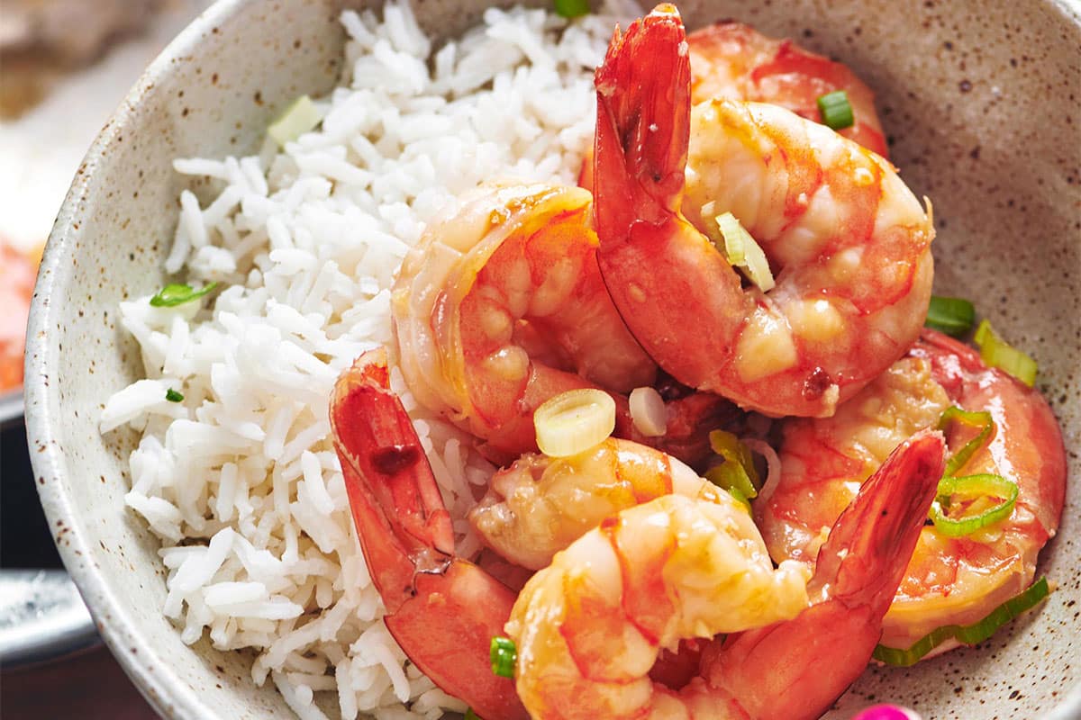 Serving honey garlic shrimp over rice in bowl.