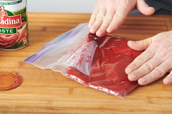 Woman pushing the air out of a Ziploc bag of tomato pate.