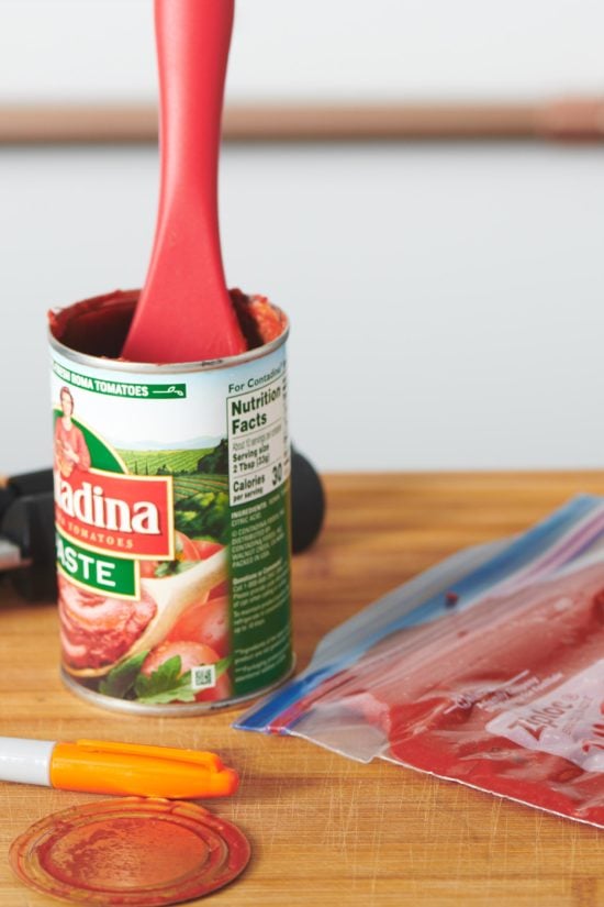 Red spatula in a can of tomato paste.