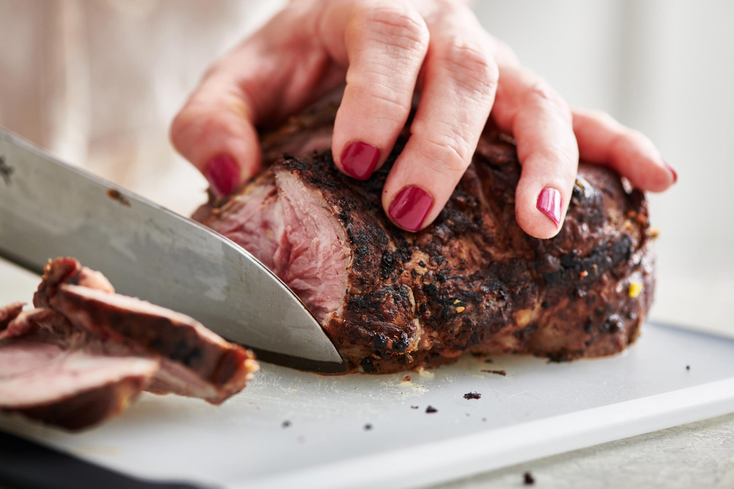 Woman slicing a leg of lamb.