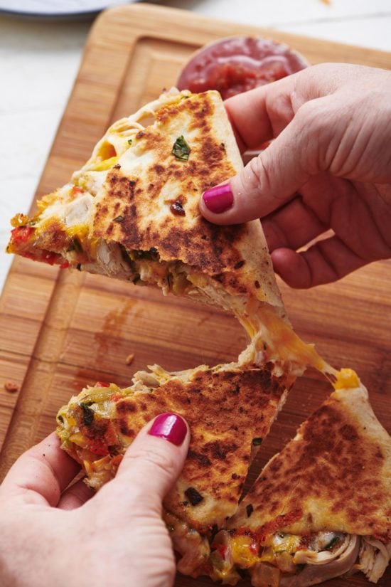 Woman pulling apart Chicken and Vegetable Quesadillas.