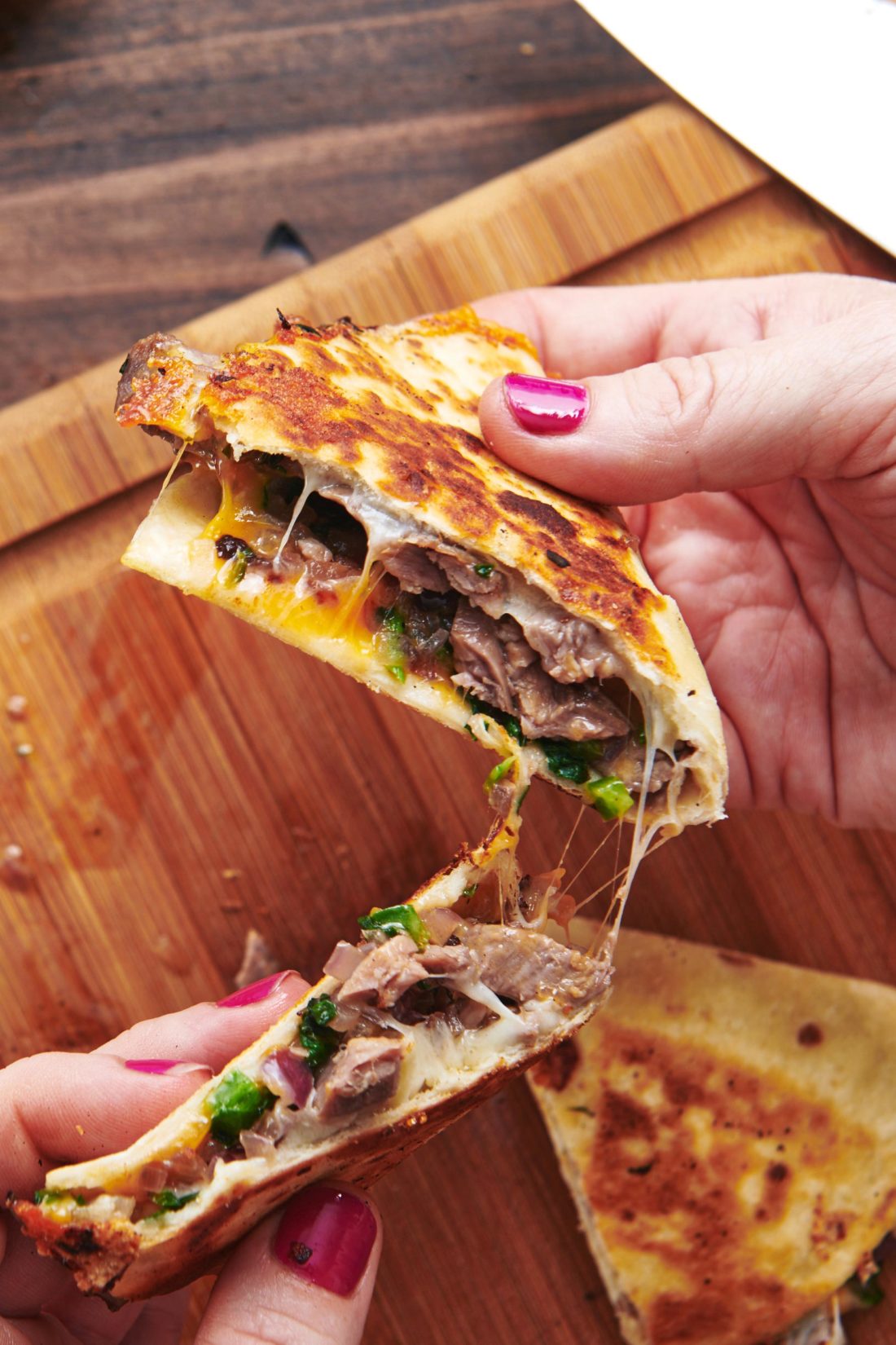 Woman holding two Steak and Cheese Quesadillas.