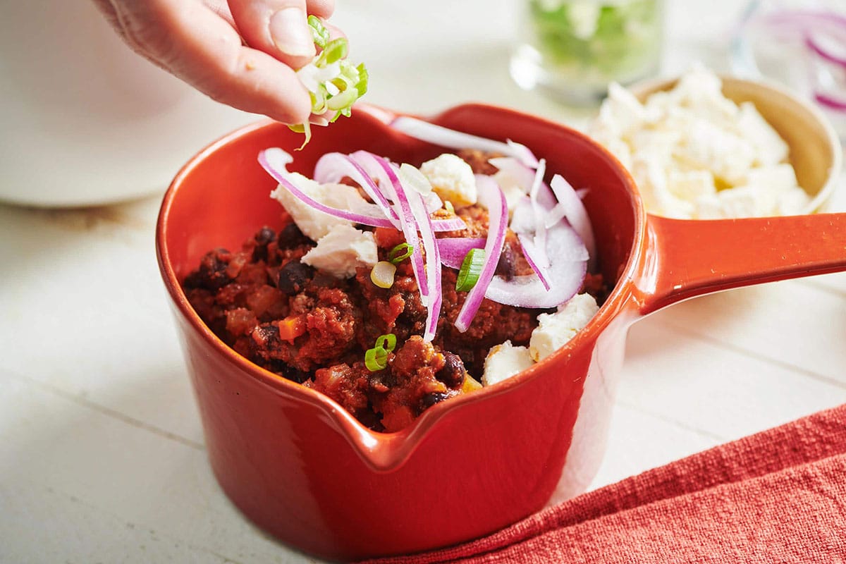 Topping beef and jalapeño chili with scallions and onions.