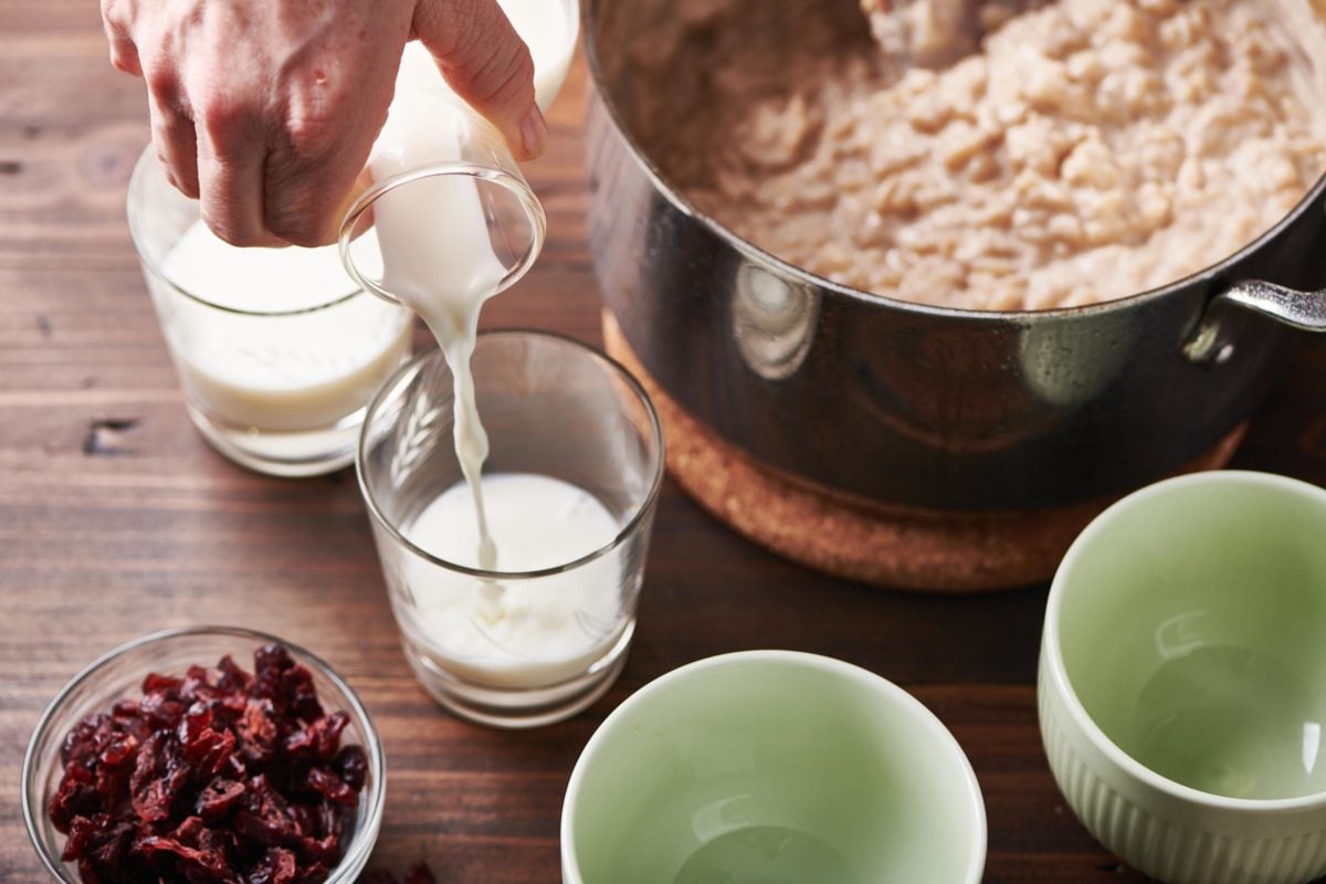 Woman pouring a glass of milk next to a pot of Creamy Rice Pudding.