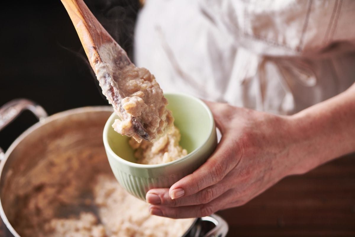 Spoon scooping Creamy Rice Pudding into a small bowl.